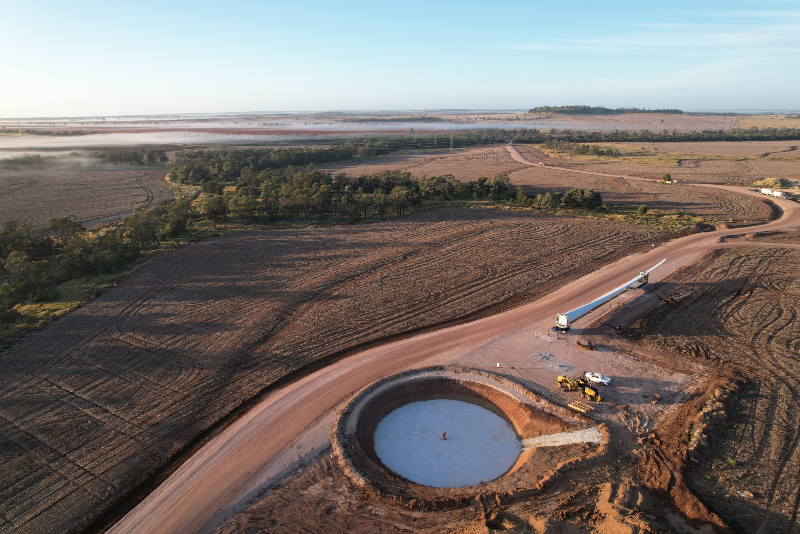 Aerial view of the Dulacca Wind Farm under construction. There are vehicles transporting materials to build turbines, and holes dug creating the foundations of the wind farm.