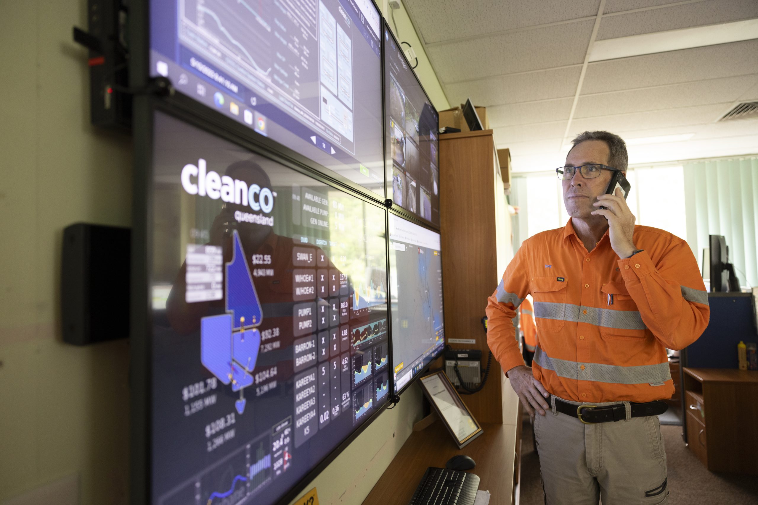 Kareeya worker looking at a TV screen with energy market information. He is talking on the phone.