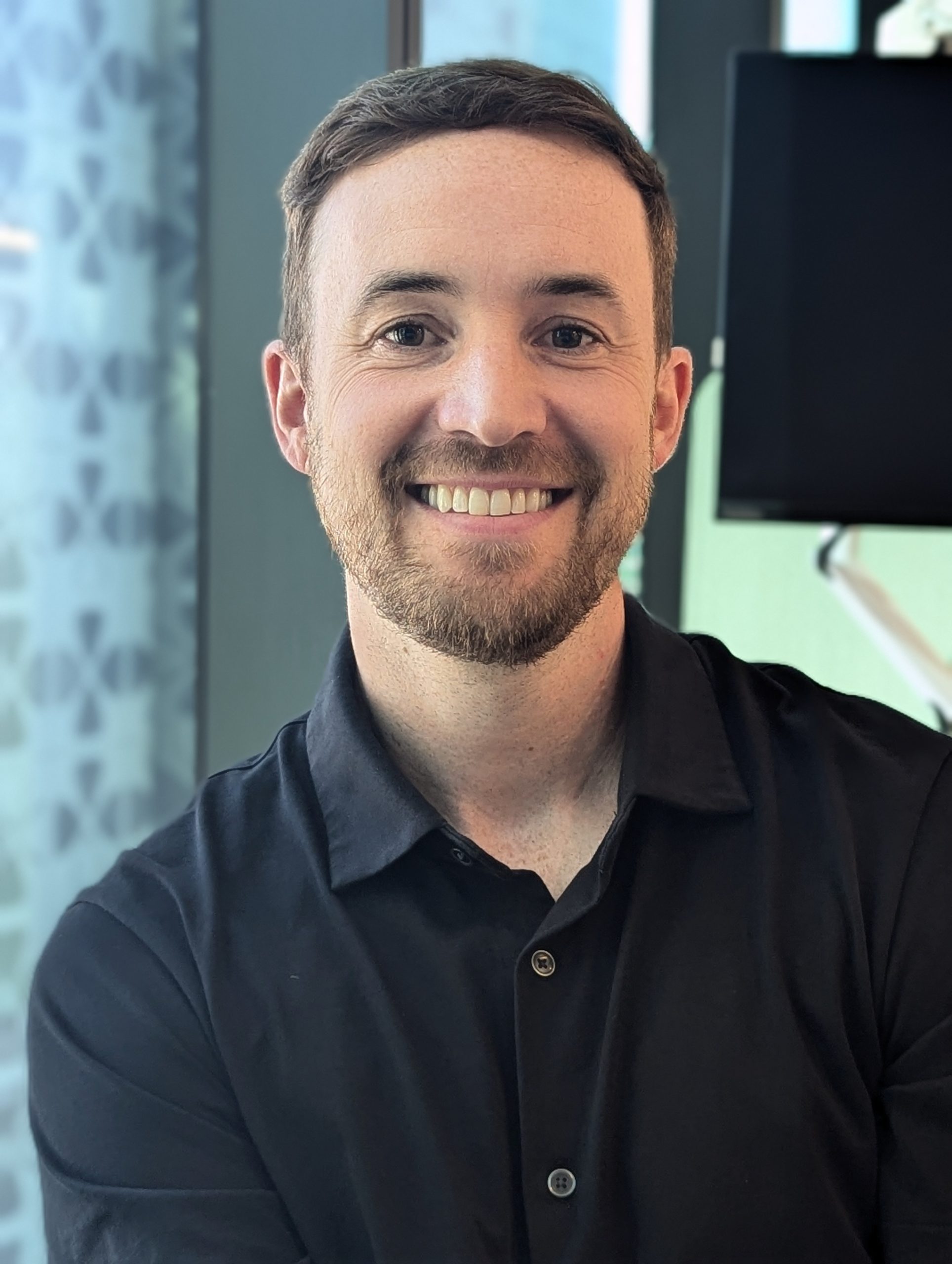 A photo of a CleanCo employee sitting and smiling at the camera, with Brisbane city skyscrapers in the background.