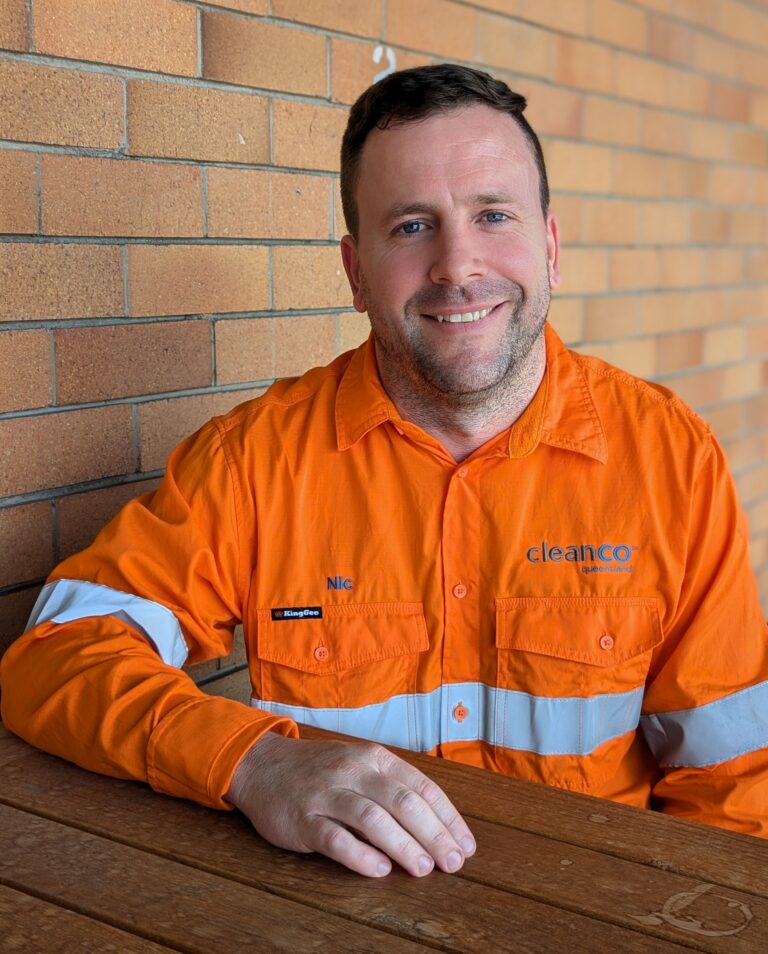 CleanCo Outage Manager Nic smiles at the camera. he is wearing high vis clothing and sits at a table.