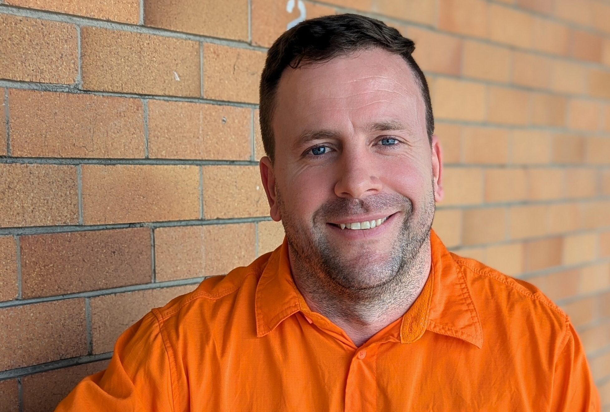 CleanCo Outage Manager Nic smiles at the camera. he is wearing high vis clothing and sits at a table.